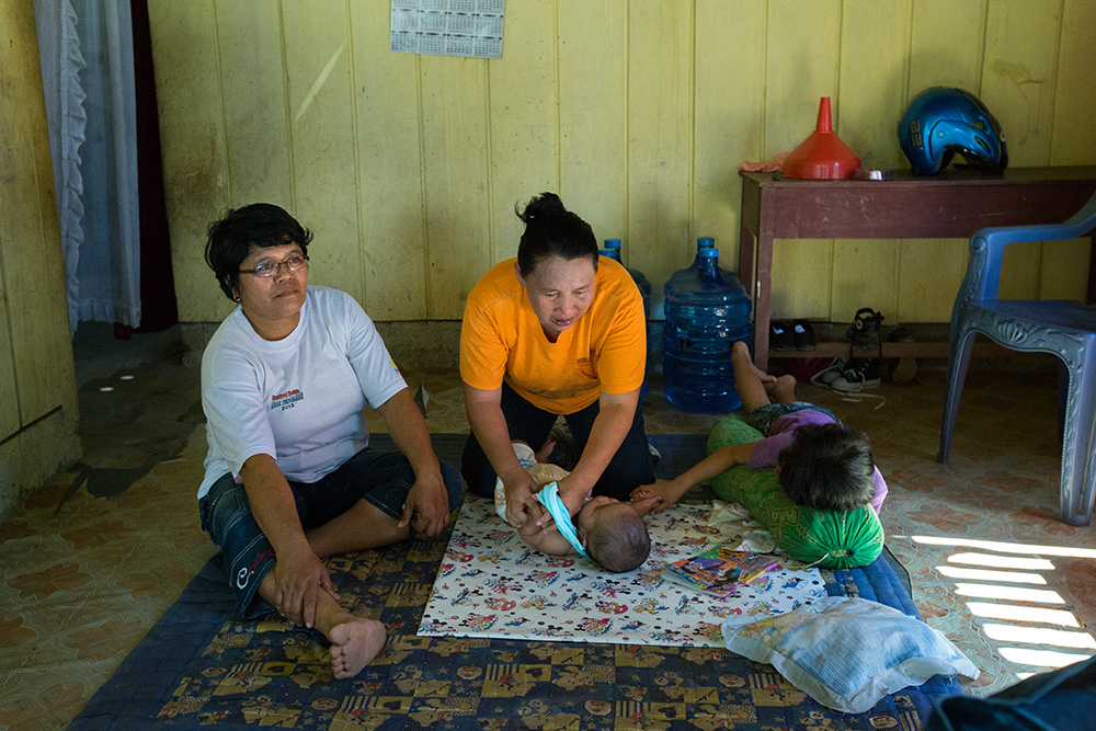 Yuyun Morangki, a sister of murdered Theresia Morangki take care of one of her babies. Mrs Martince (left) represent Mosintuwu Institute - an organization promoting tolerance between Muslims and Christians in Poso.