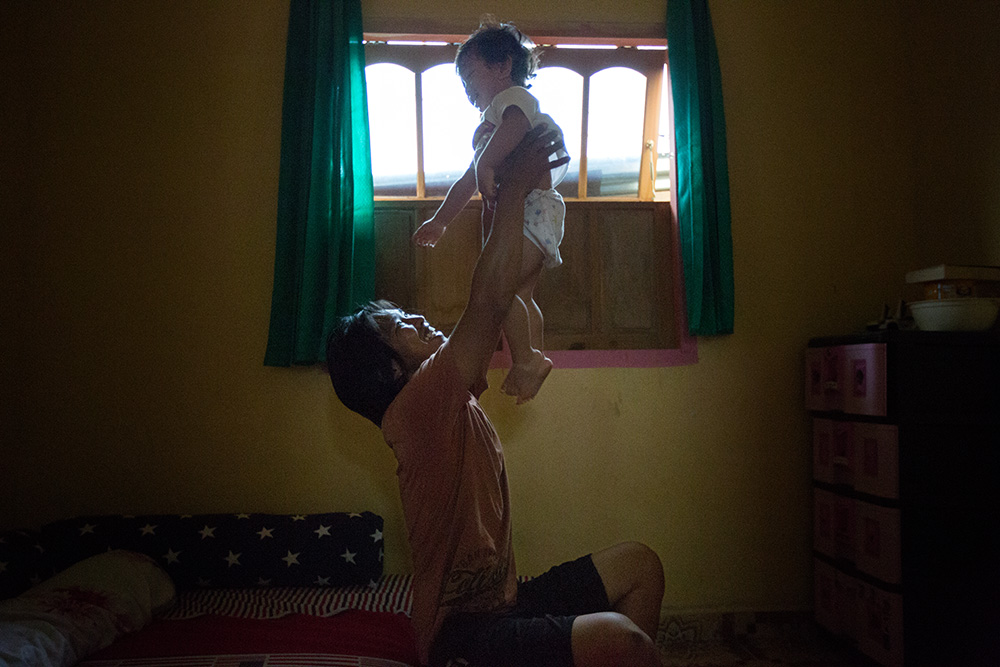 Tentena. Frans Toheba (27), husband of Yulin Mbatono, play with his son Steve (2) in a bedroom.