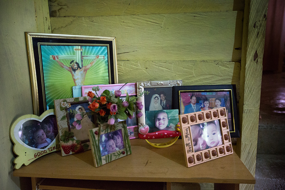 Religious picture with family photos on a table in Kia Wundu's relatives house.