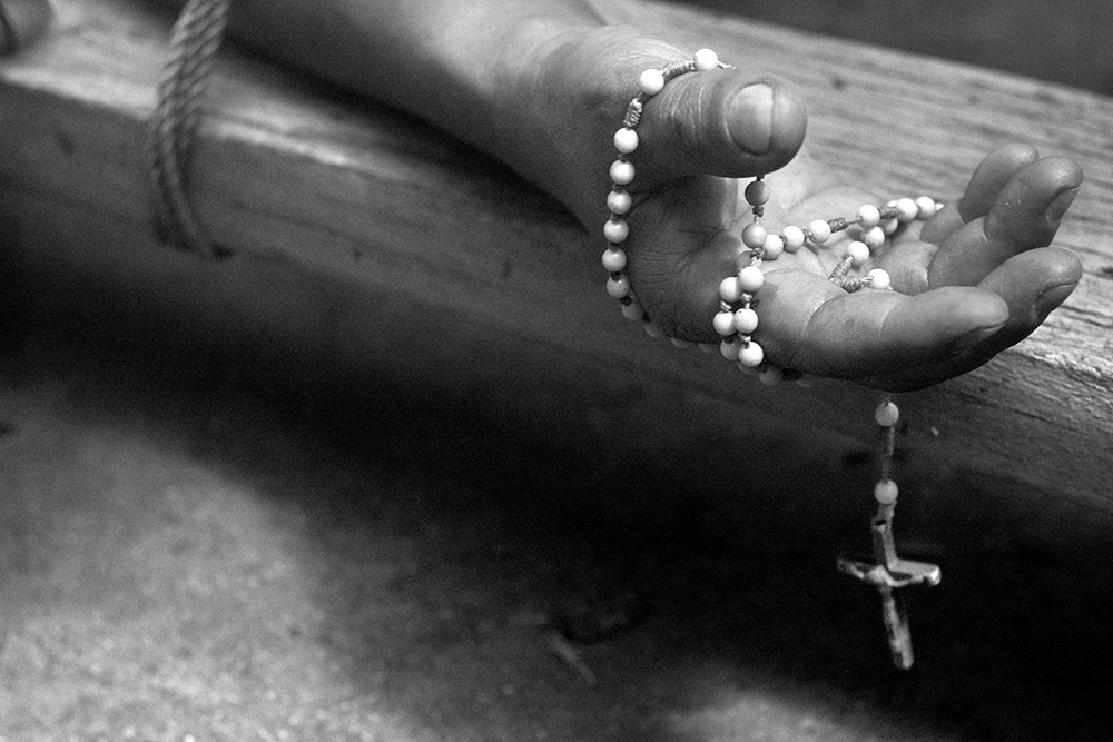 Good Friday. Attached to a cross one of the martyrs' hand holds a Catholic rosary.
