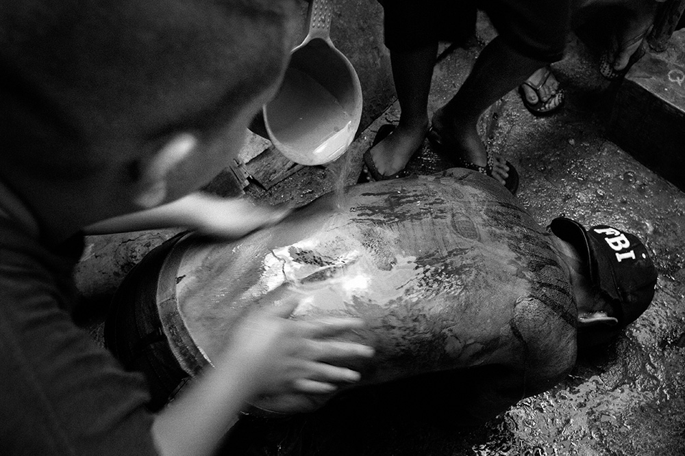 A man after the flagellation performance is having his back cleaned with water.
