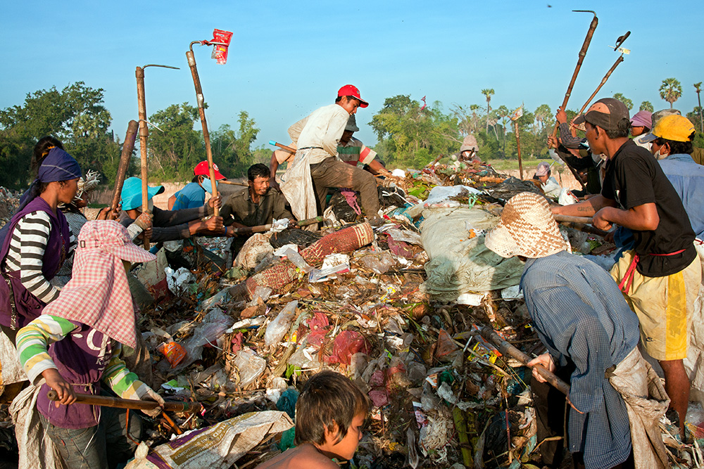 Garbage dump residents browse recently dumped waste looking for recyclable material or any other useful objects. Families compete with each other to find the most valuable items.